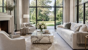 Bright, elegant living room with floor-to-ceiling windows overlooking a landscaped yard